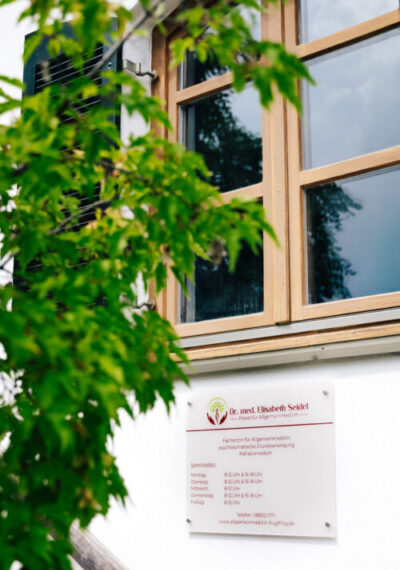 Nahaufnahme des Schildes der Arztpraxis an der Fassade des Gebäudes unterhalb eines Fensters